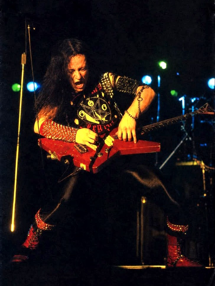 Live performance photograph of Venom vocalist and bassist Conrad ‘Cronos’ Lant on stage.